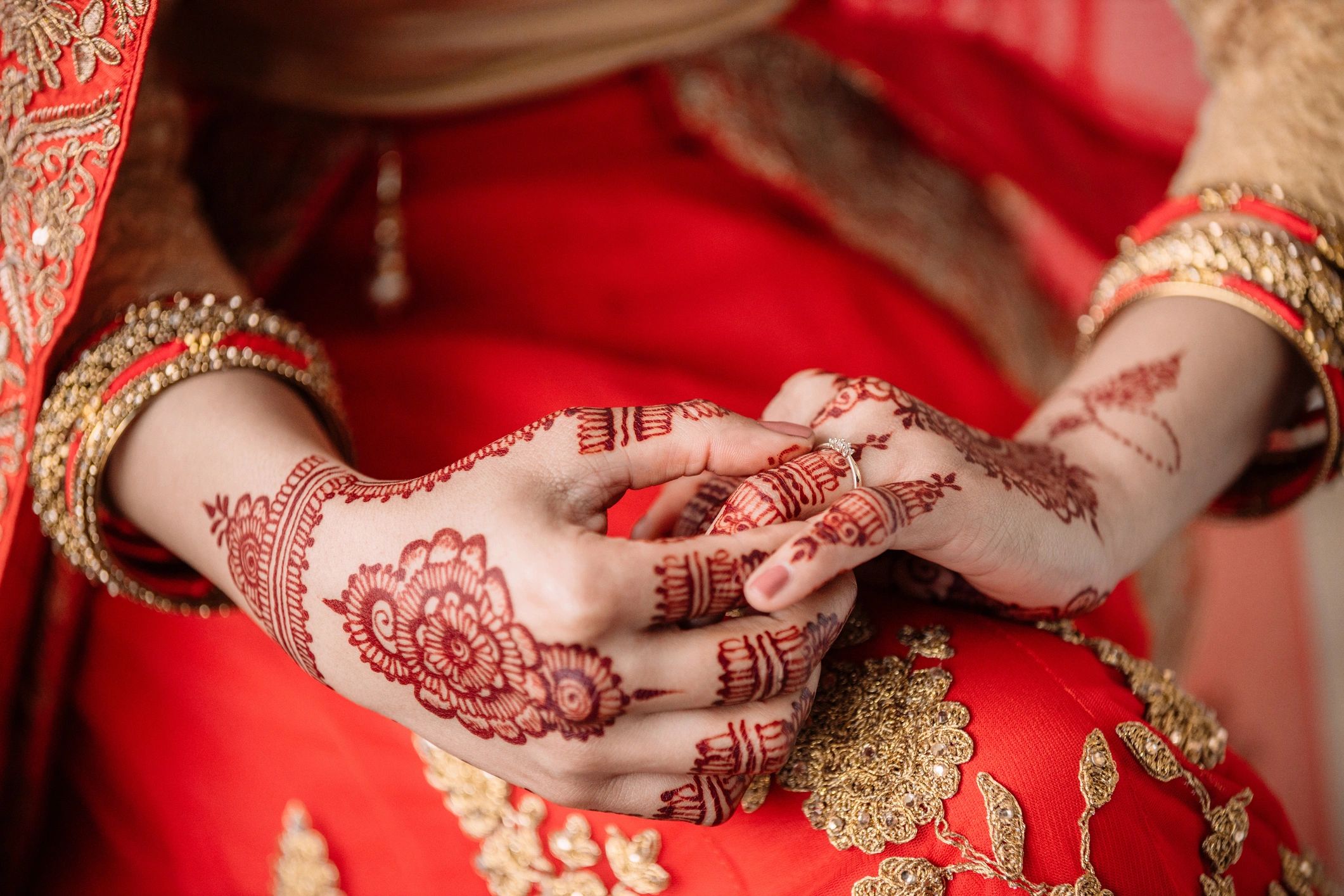 Bride holding ring with mehndi details